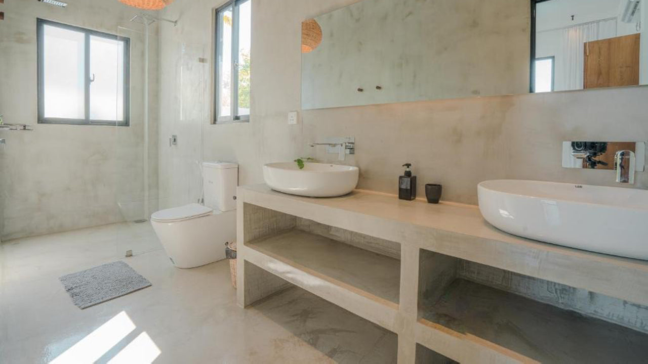 Modern bathroom with two white sinks on a wooden vanity, large mirror, and natural light.