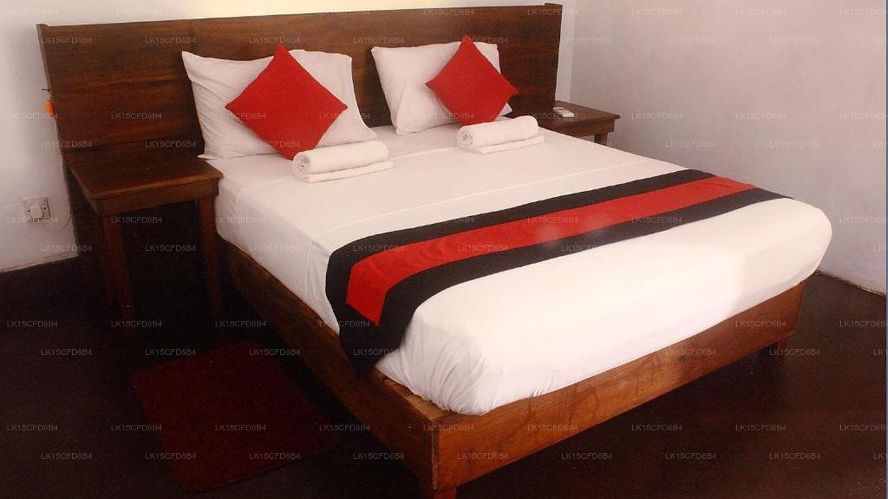 Bed with red and black decorative pillows and bedspread in a room.