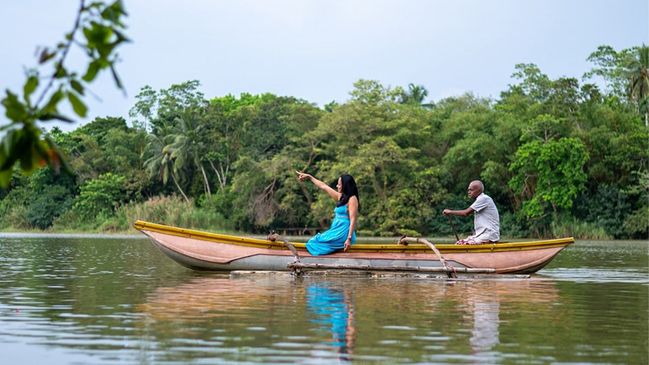 Two people in a canoe on a calm body of water with greenery in the background