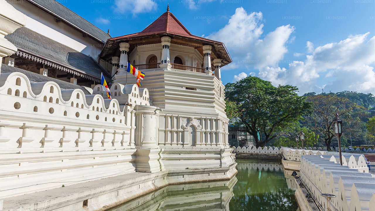 Temple of the Sacred Tooth Relic in Kandy, Sri Lanka, with white walls, traditional architecture, and Buddhist flags.