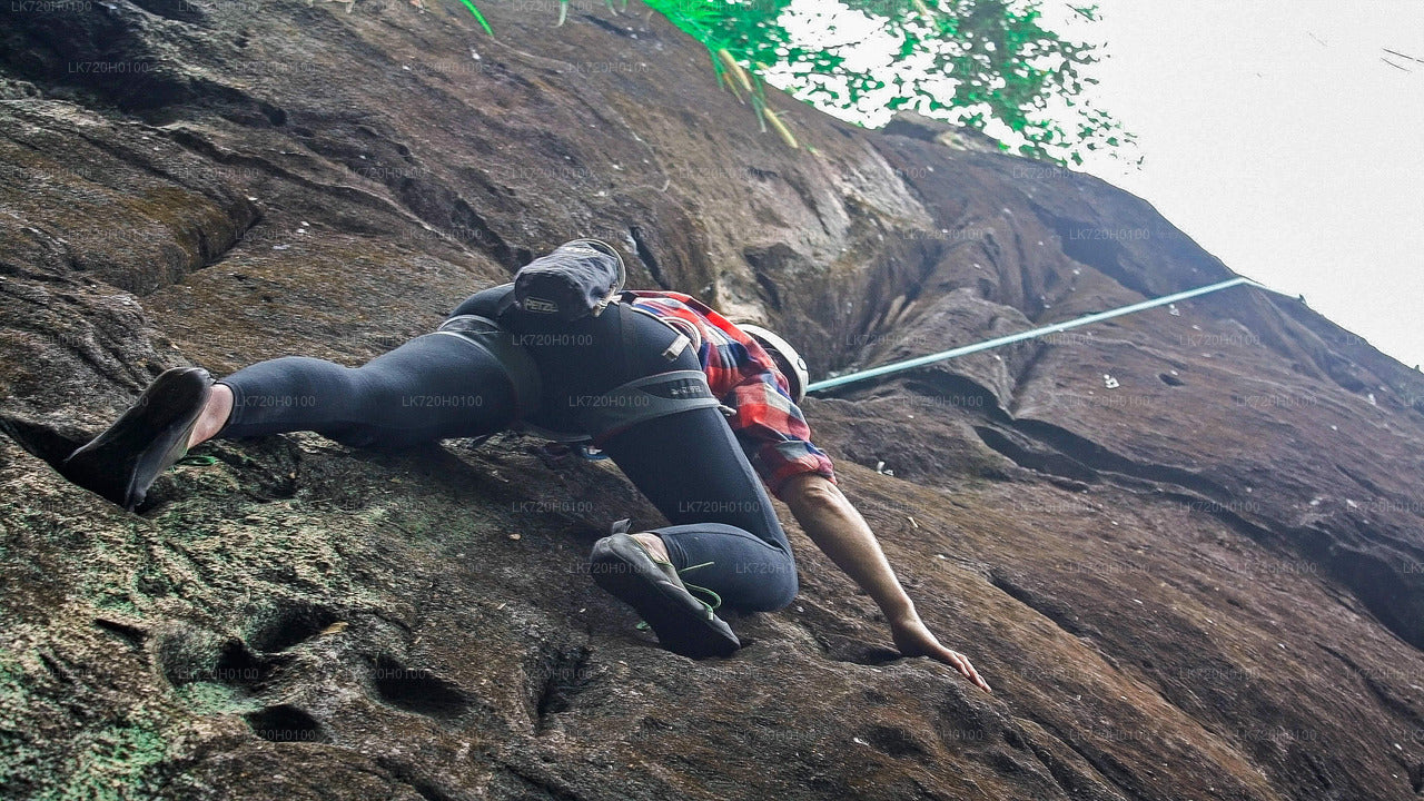 A person climbing a rock face with a rope, wearing a red and black outfit with a visible brand logo.