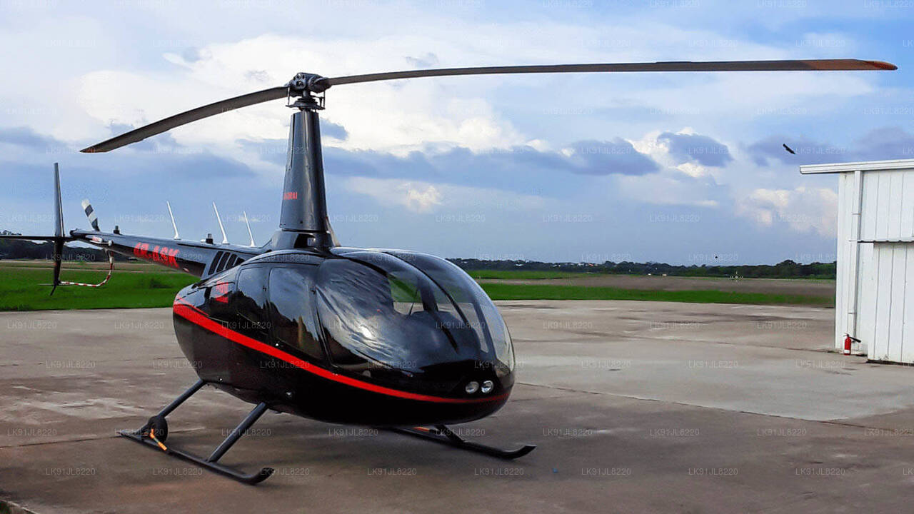 A black Robinson R66 helicopter with red and gray detailing on the front, seen from a side angle with a cloudy sky in the background.